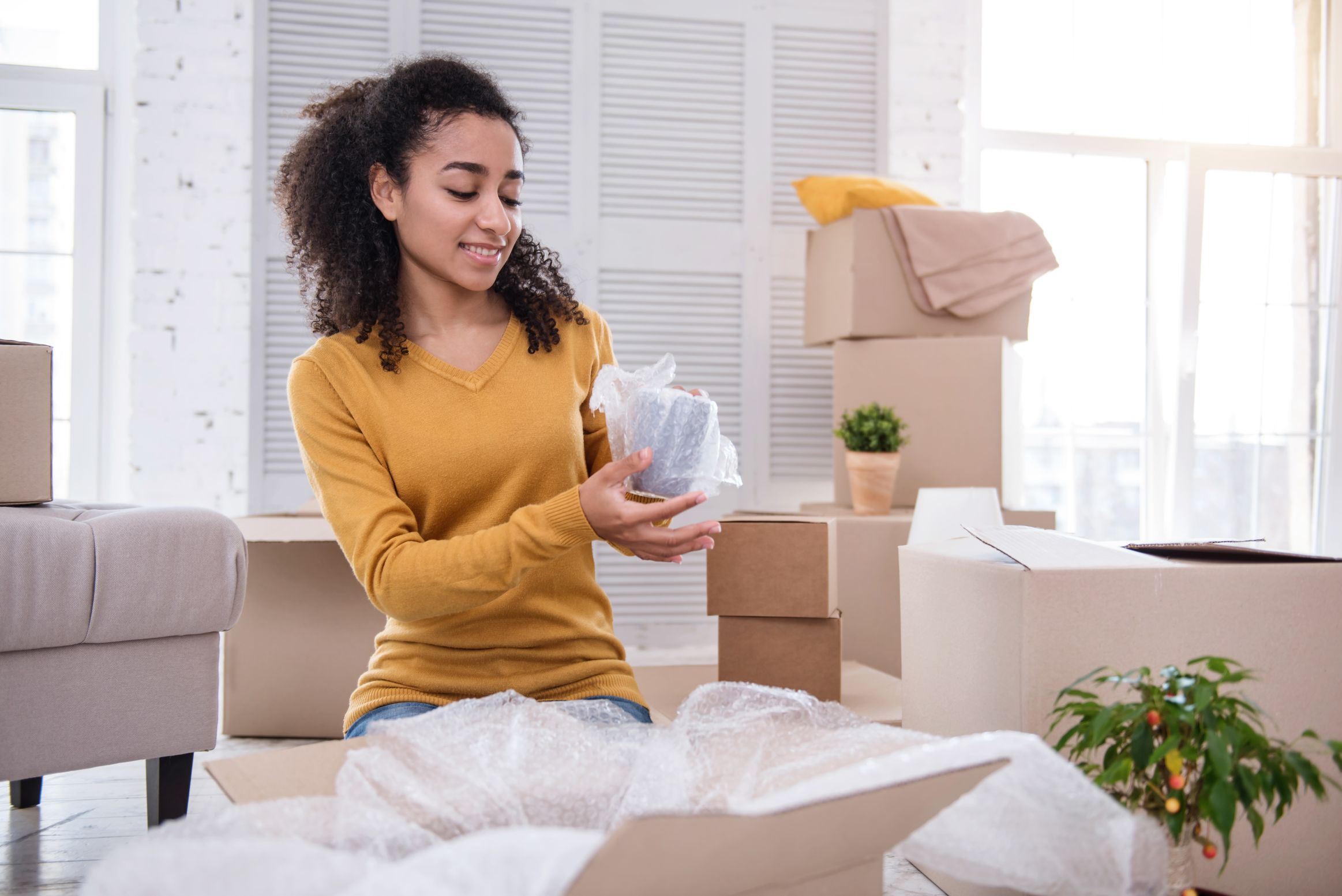 A girl at home wrapping up a cup in a bubble wrap without any help from movers