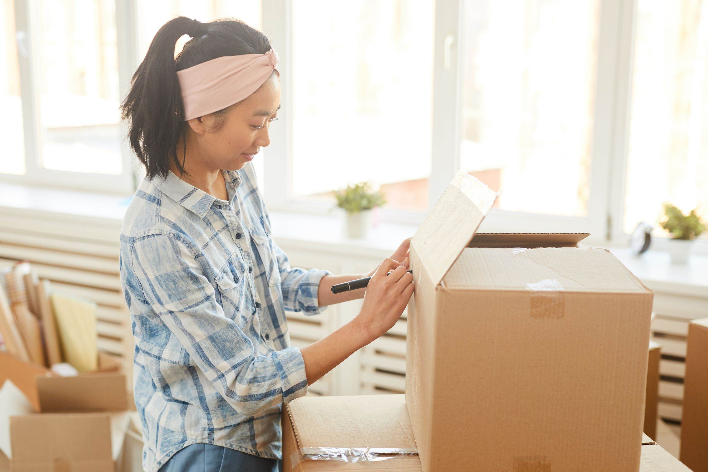 A woman writing a label on a new box