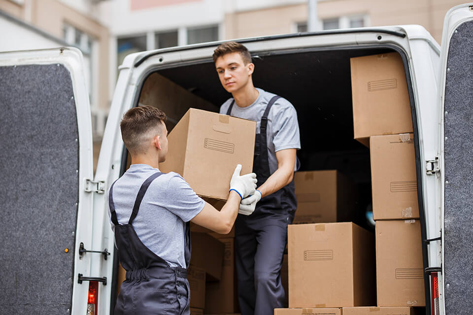 Two movers putting cartons in the truck