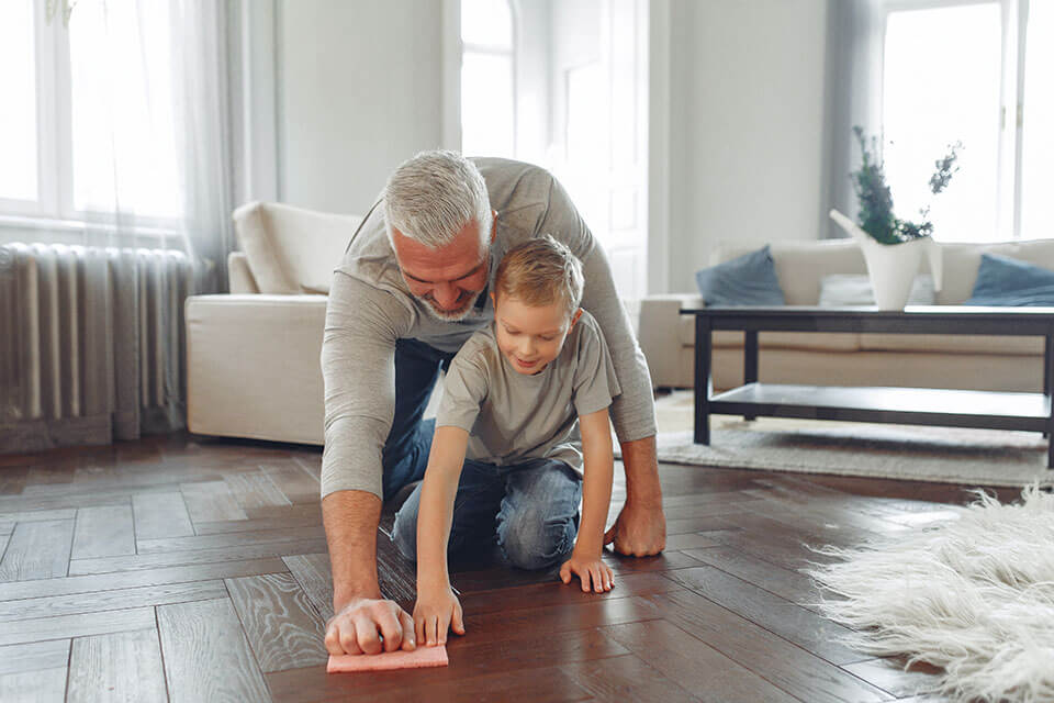 A boy and an older man cleaning a floor