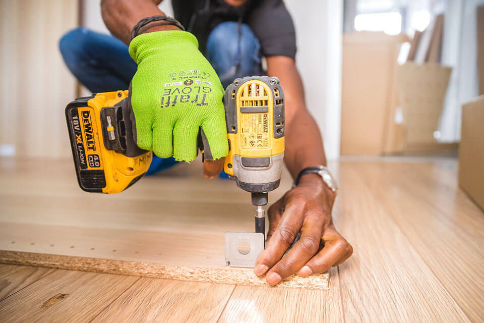 a man unscrewing table legs and preparing furnishings for a moving company