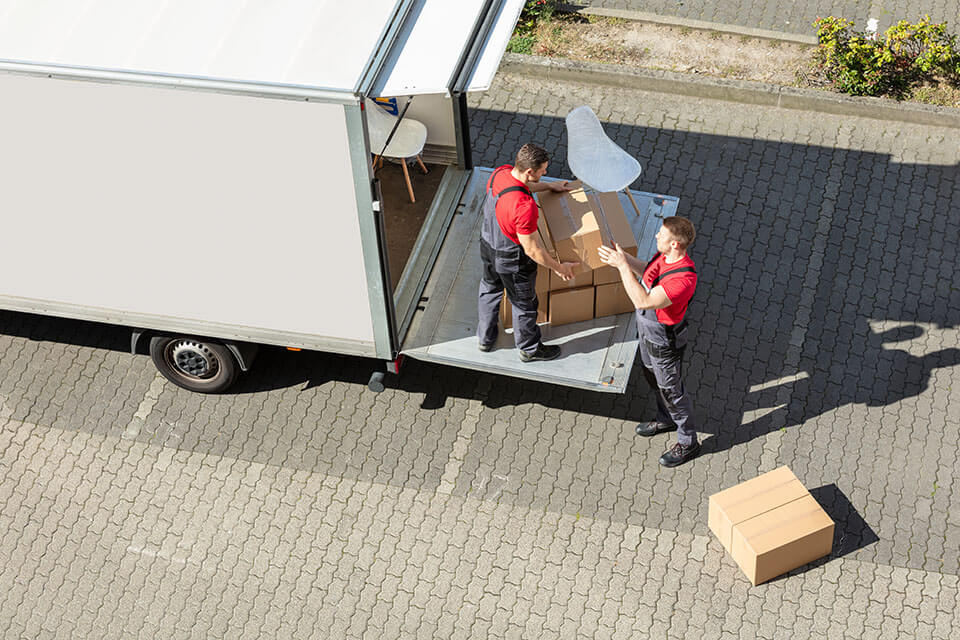 two movers packing chairs and containers into the relocation truck