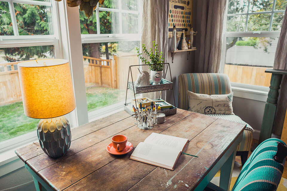 an old wooden table placed in front of a window that overlooks a backyard