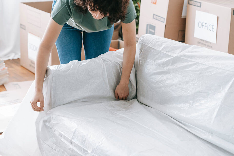 a woman in a green t-shirt packing her couch and preparing for a moving company