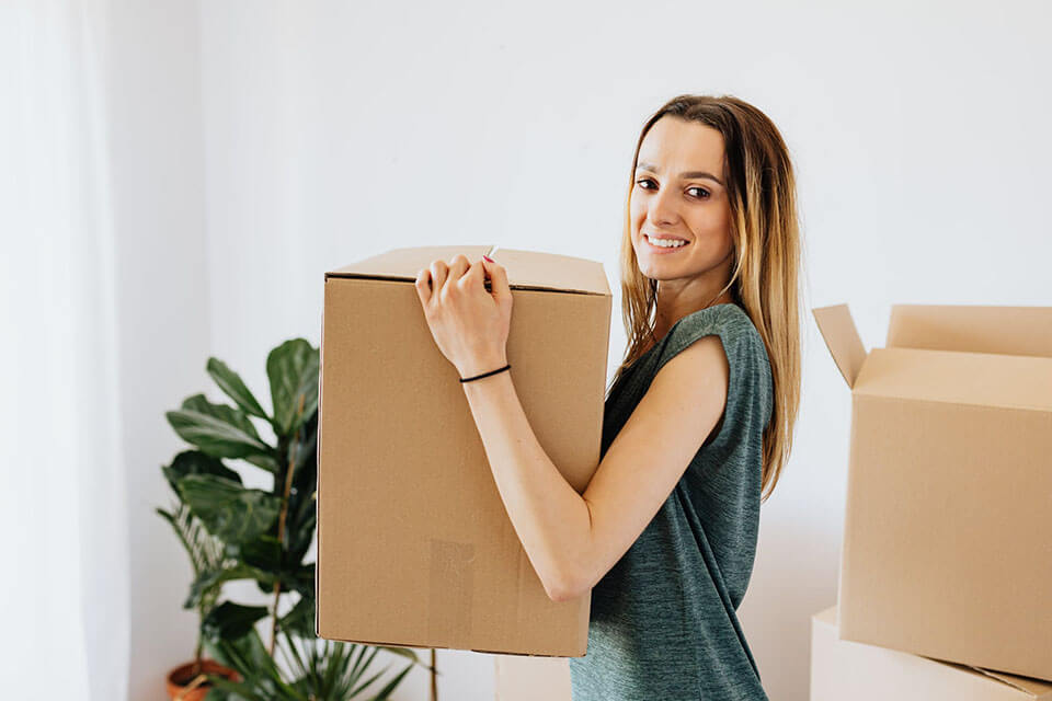 A girl holding a box and smiling after finding a moving app