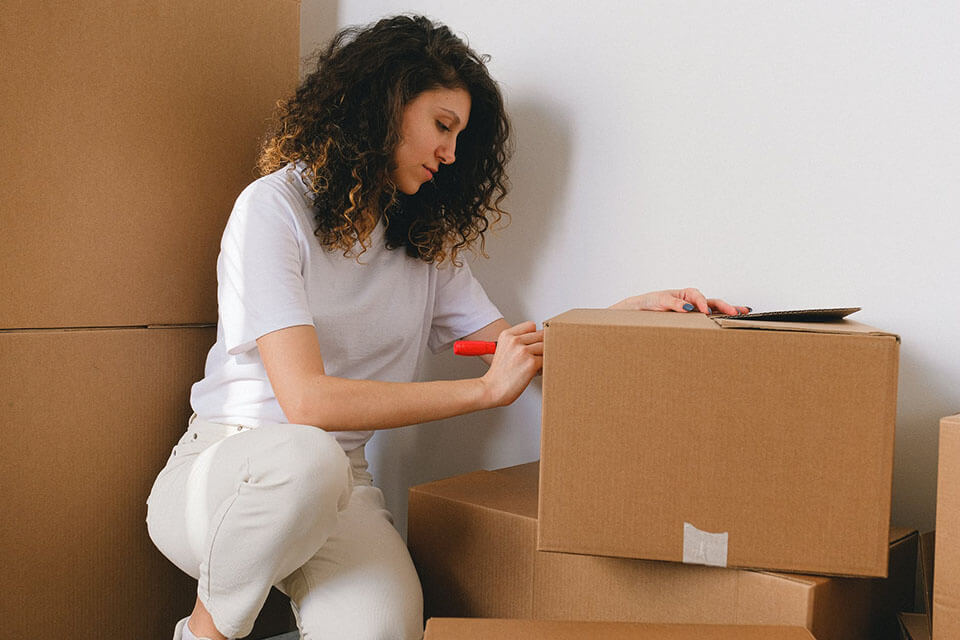 A woman writing labels on the boxes after she found an app to compare moving companies