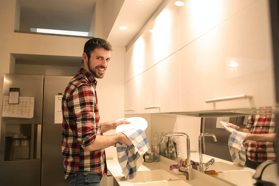 a man washing dishes and smiling