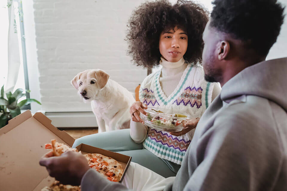 a young couple and their dog eating dinner together