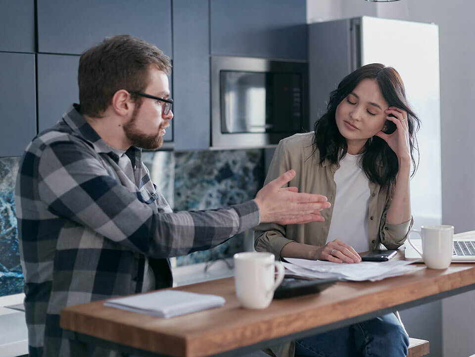 a couple sitting with calculators and documents and arguing