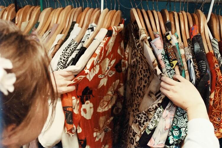 Girl going through shirts on a clothing rack