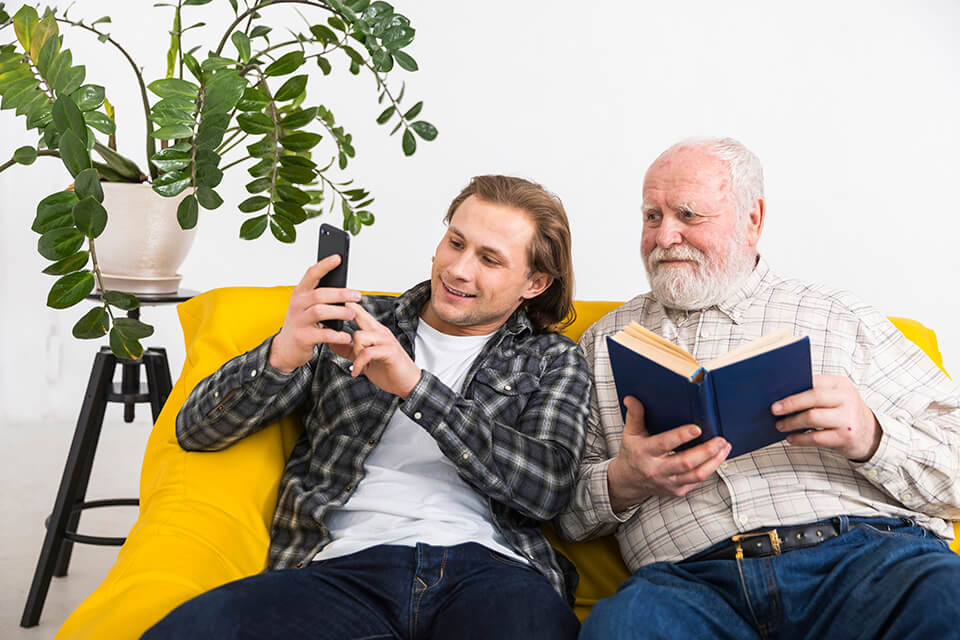 Father and son sitting on the yellow couch, taking a selfie