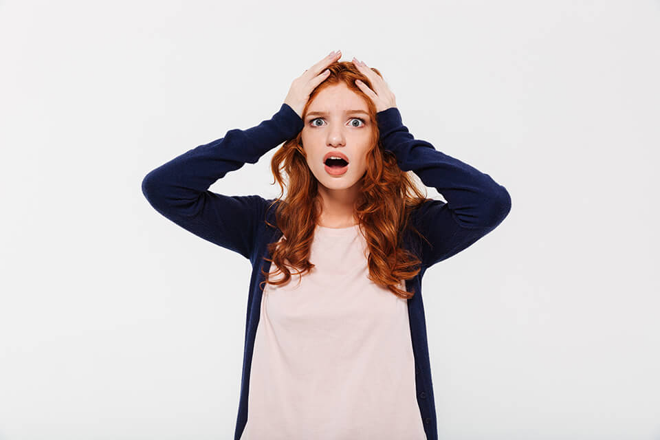 A redhead girl holding her head in shock