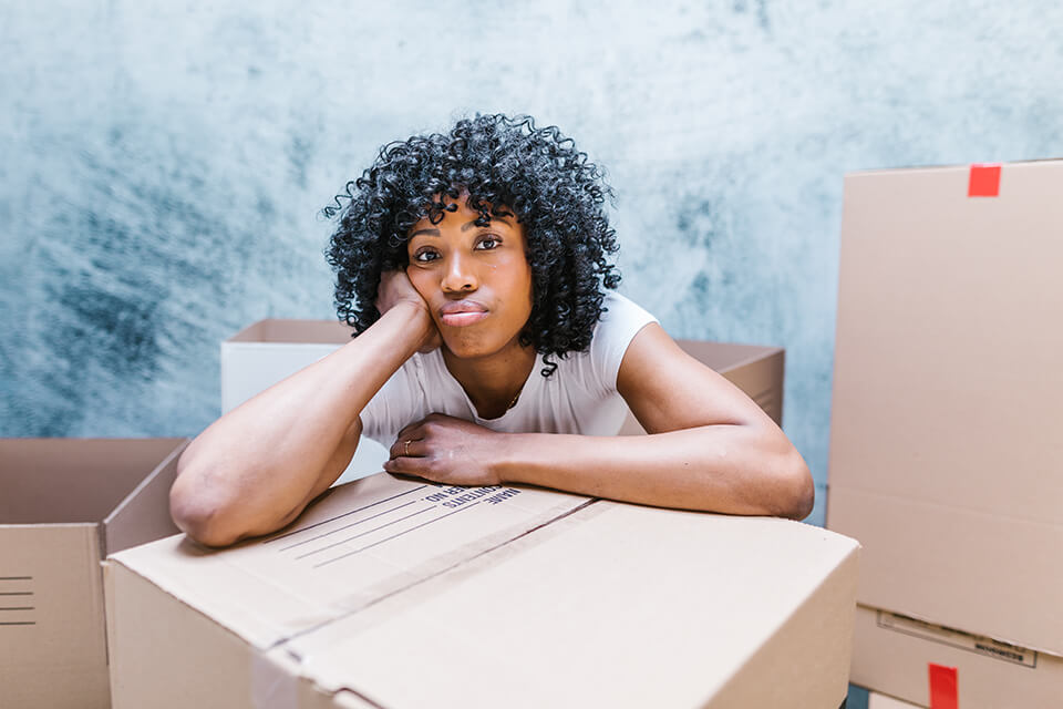 A sad girl leaning on packed boxes