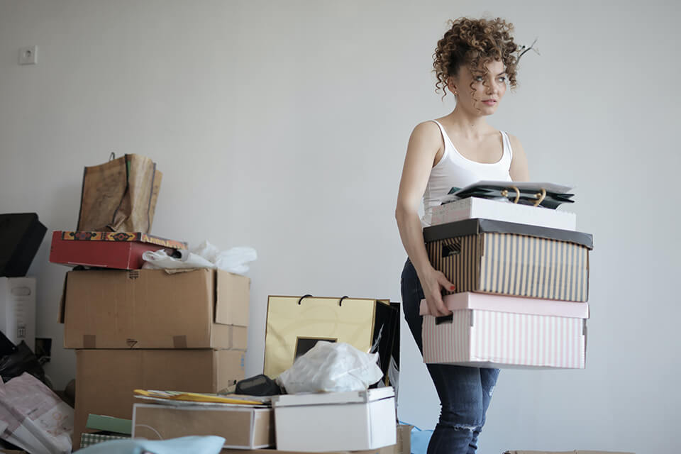 Woman carrying boxes, a pile of boxes behind her